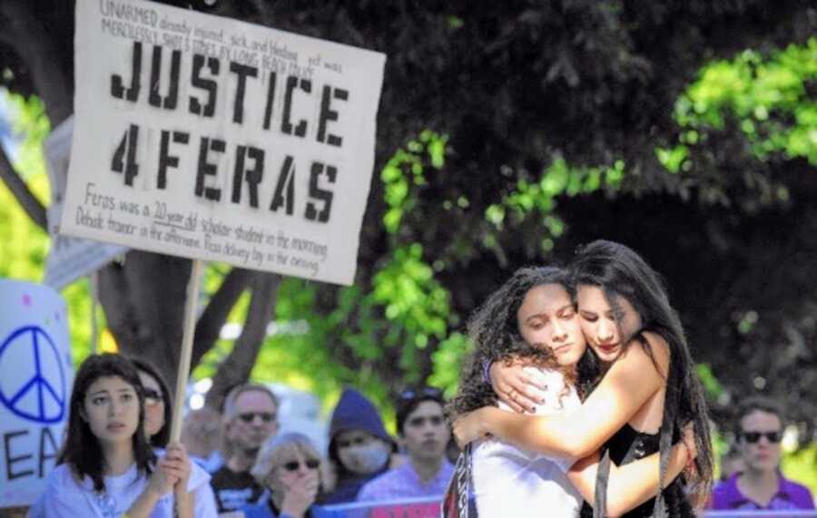 Two women hugging at a rally for social justice