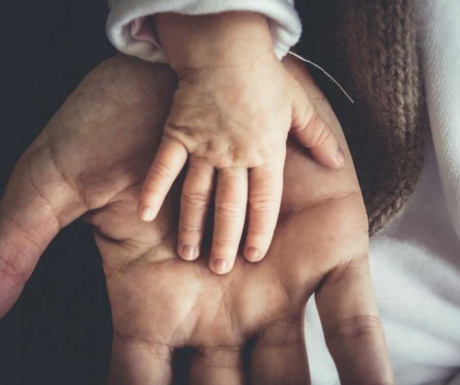 Toddler places hand in father's palm.