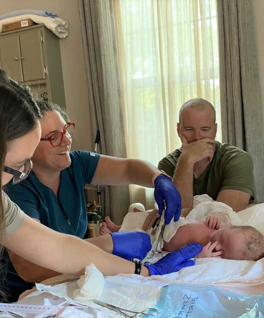 Proud Dad watches as the midwives weigh and measure new baby.