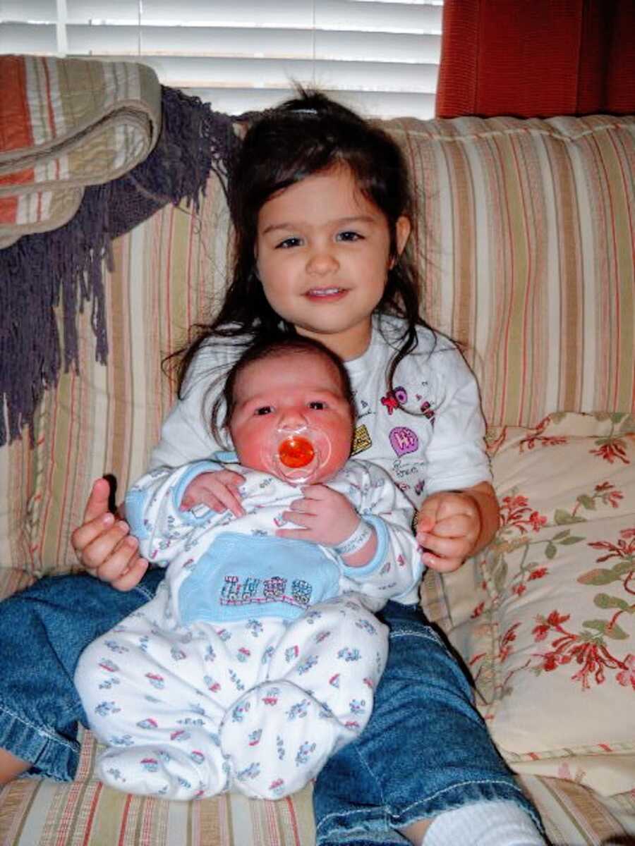 Little girl holds her baby brother on her lap