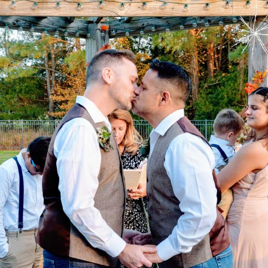 Gay men kissing at their wedding