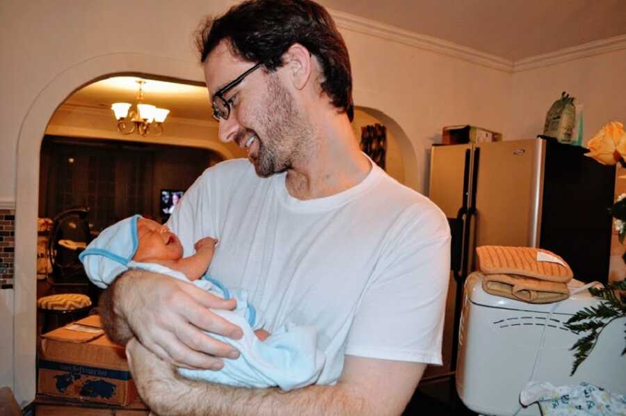 Man holds his newborn son in his arms