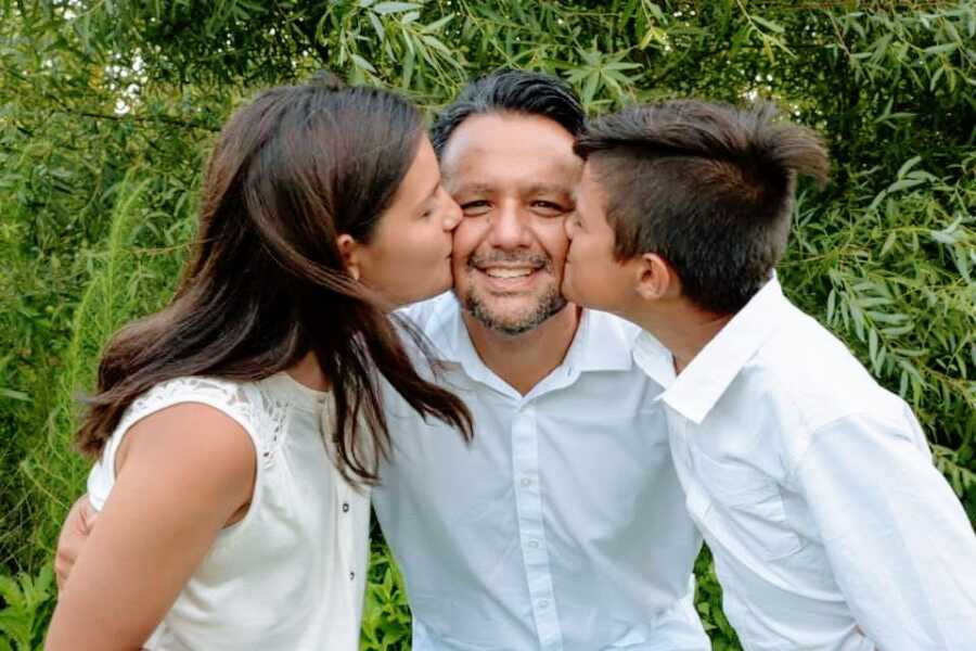 男人和他的两个孩子亲吻他的脸颊