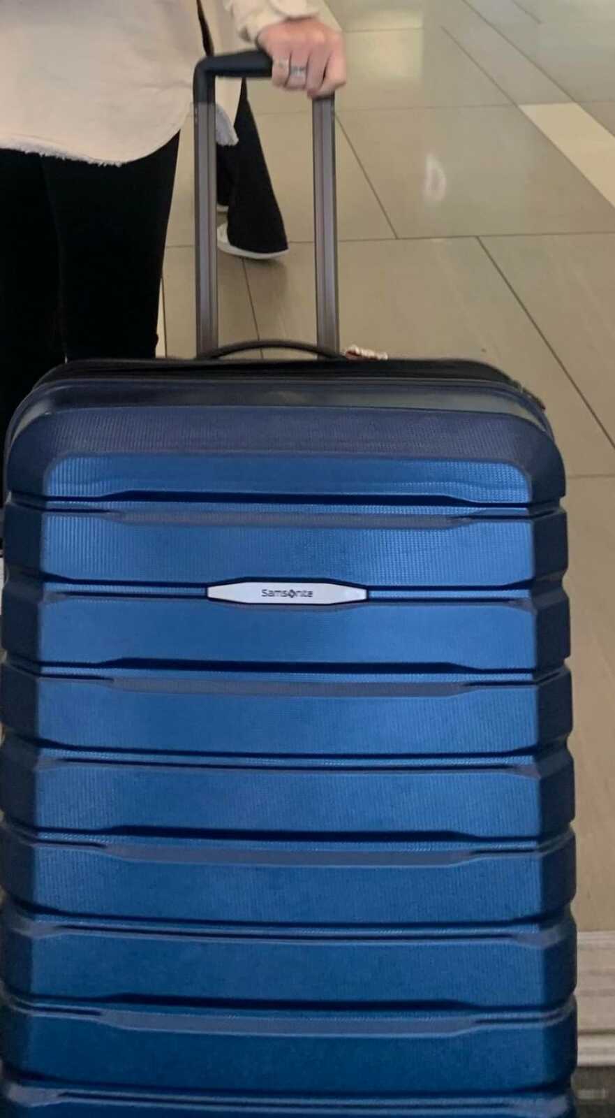 daughter taking her luggage through the airport leaving her parents