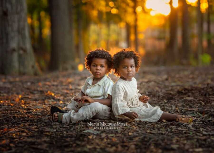 adoptive twins sitting on leaves for a photo shoot