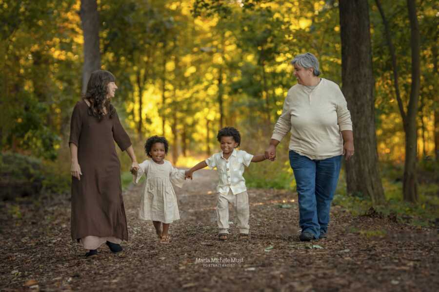 adoptive parents with their twins holding hands