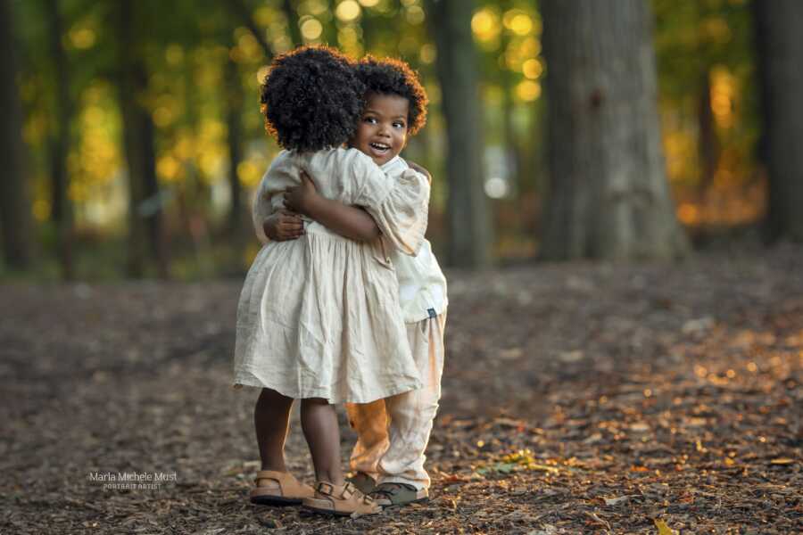 twins in white hugging each other close smiling