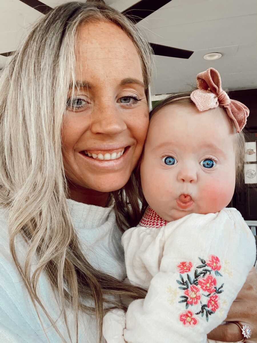 mama taking a selfie with baby girl with bright blue eyes making a funny face