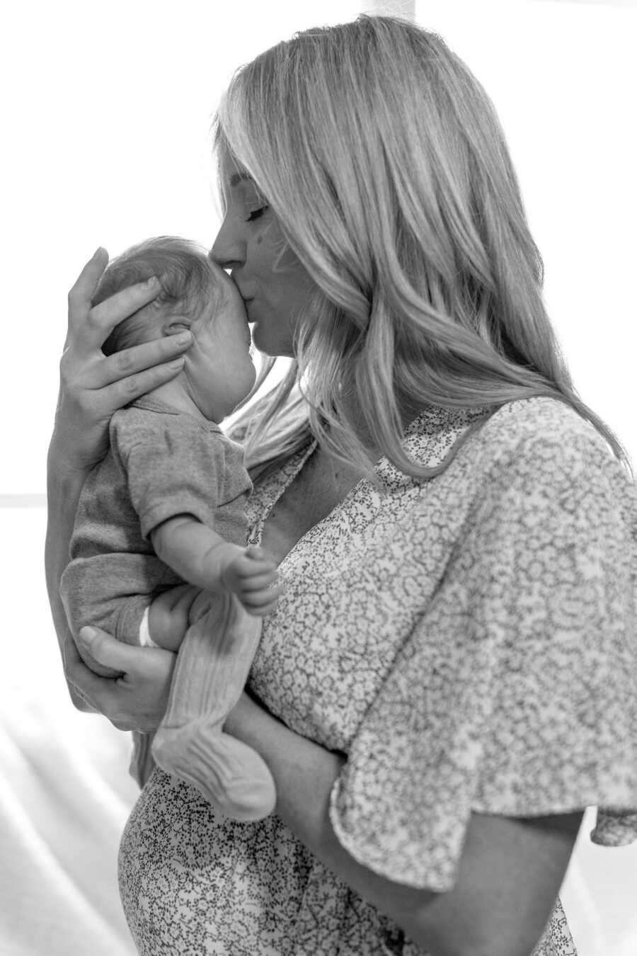 mom kissing her new born daughter on the forehead