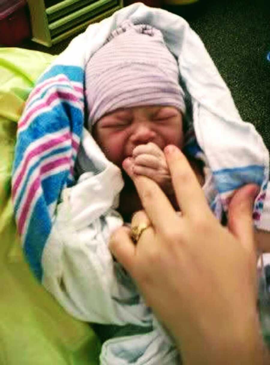 Crying newborn baby swaddled in hospital blanket