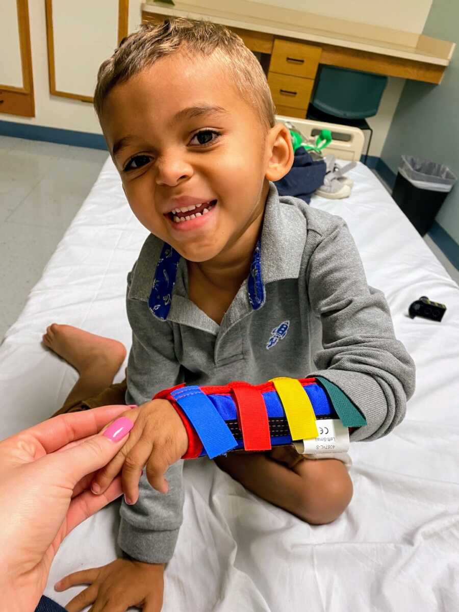 toddler boy smiling and wearing a wrist brace 