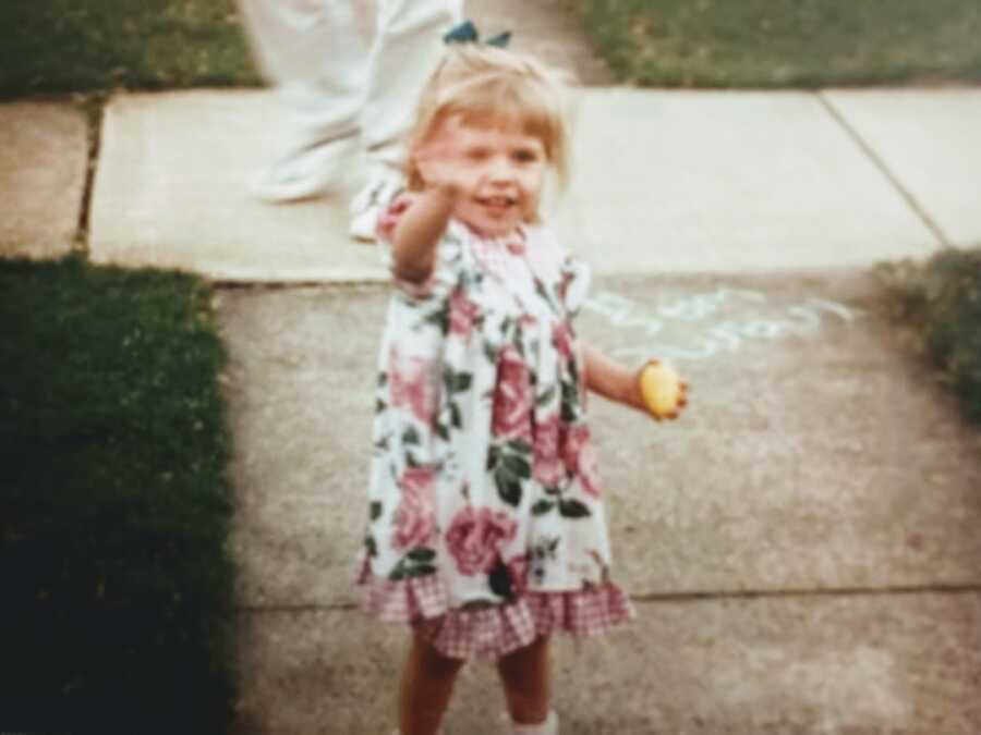 一个穿着粉色碎花连衣裙的小孩在镜头前挥手