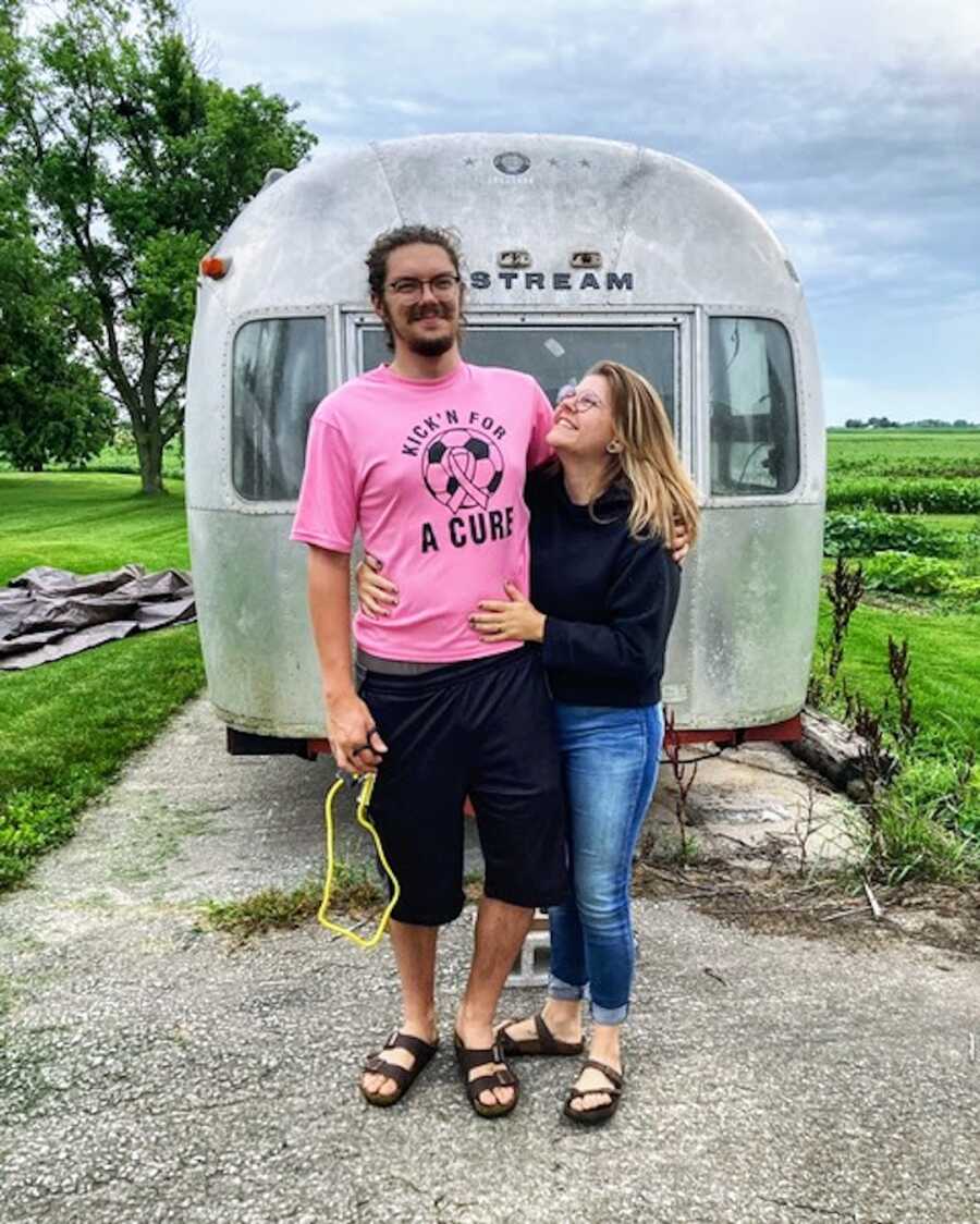 Woman and husband in front of vehicle smiling together