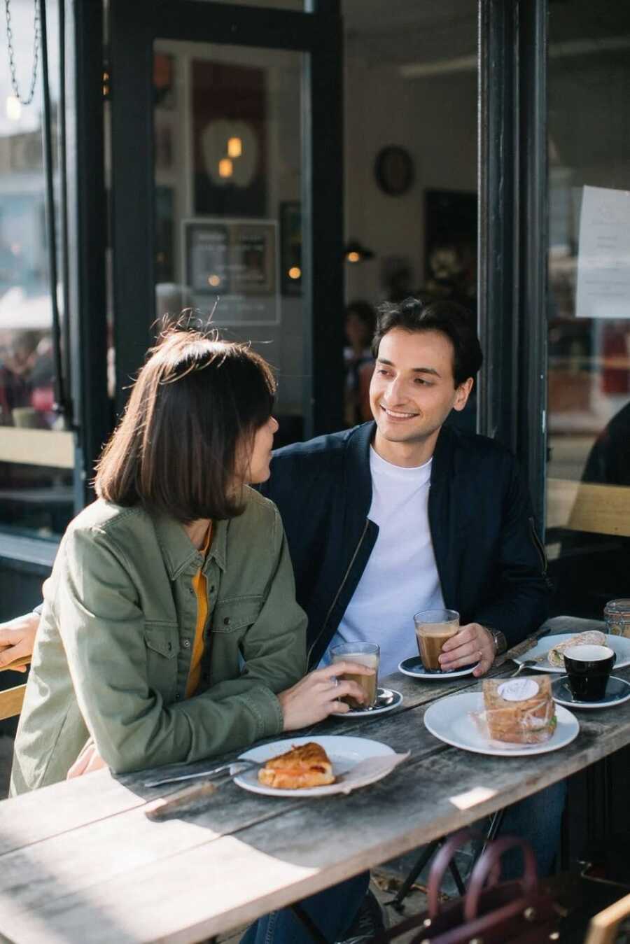 couple out on a date in a coffee shop while sitting in the sunlight