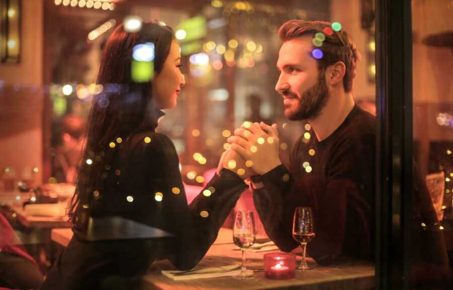 couple holding hands at a restaurant on a date night 
