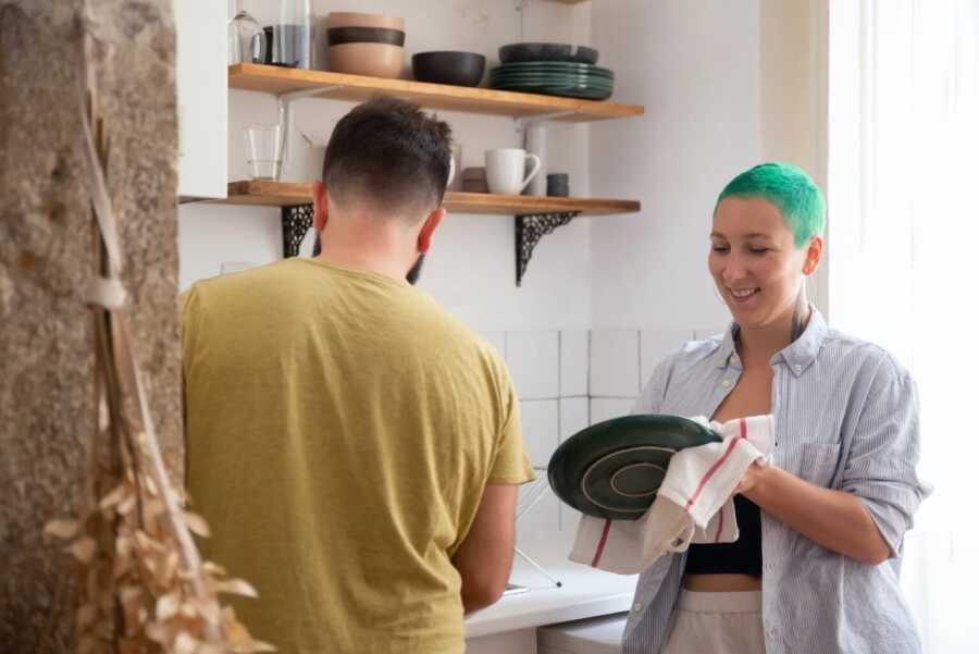 couple doing dishes together while posing for a picture