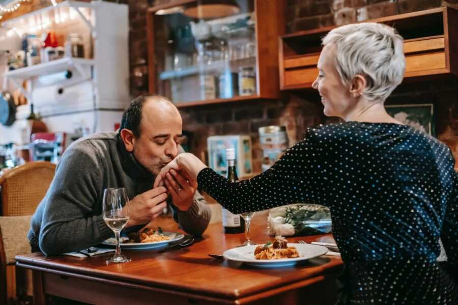 man kissing his partners hand while out on a date