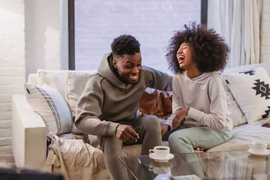 couple sitting on their couch laughing at a joke