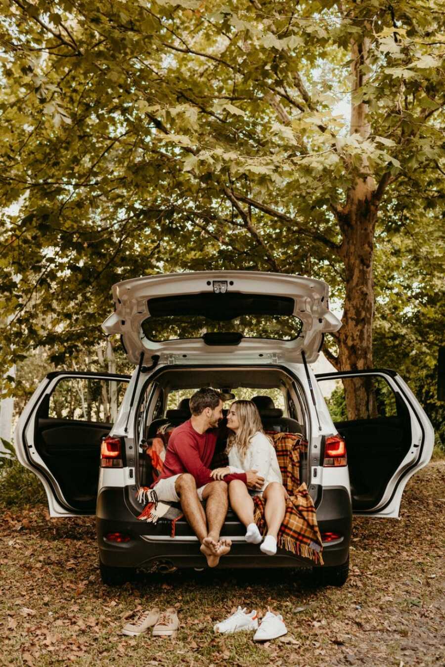 couple in their car snuggling up to each other in the forest while having a date night