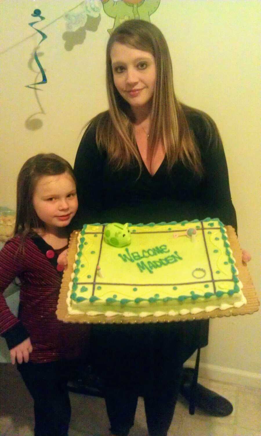 Mom holding a cake while standing next to her daughter.