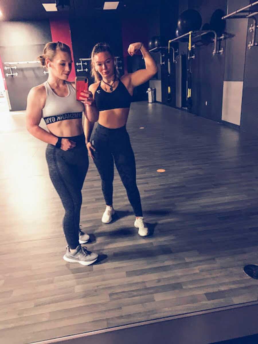 Mom and daughter posing for selfie at a gym.