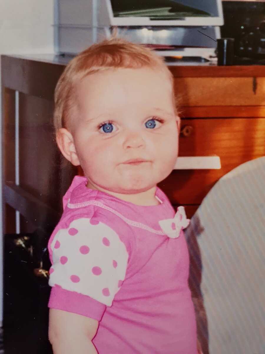 Autistic child with big blue eyes wearing a pink outfit