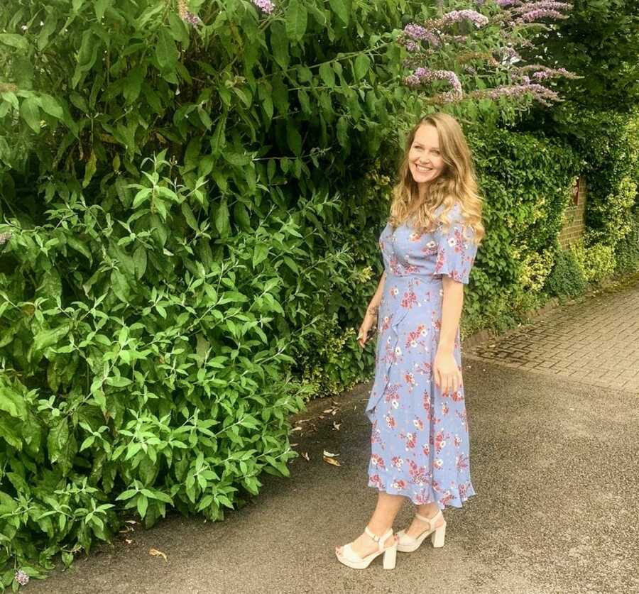 woman in dress smiling next to beautiful green plants