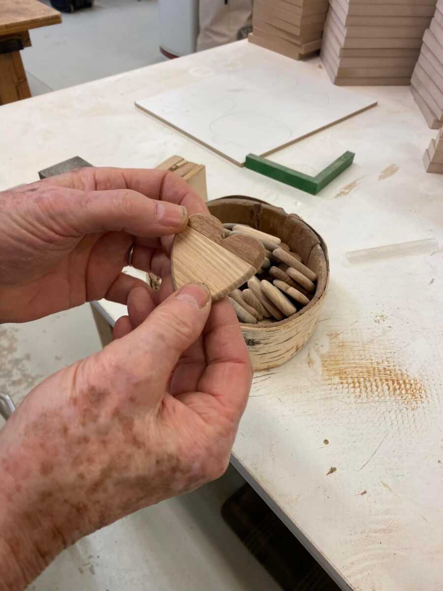 man holding his wood heart to show how it looks after