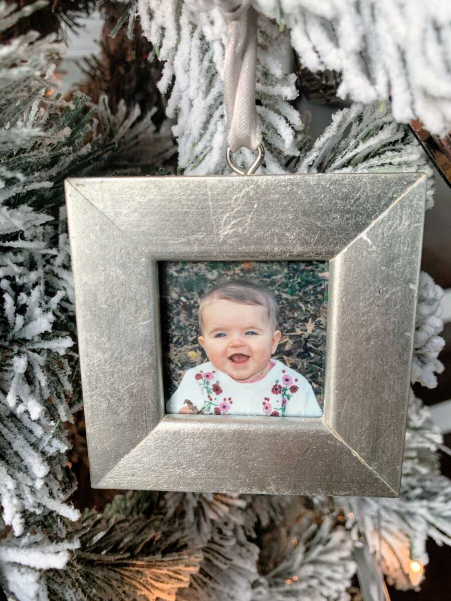 Portrait of little girl with big smile hanging on a Christmas tree