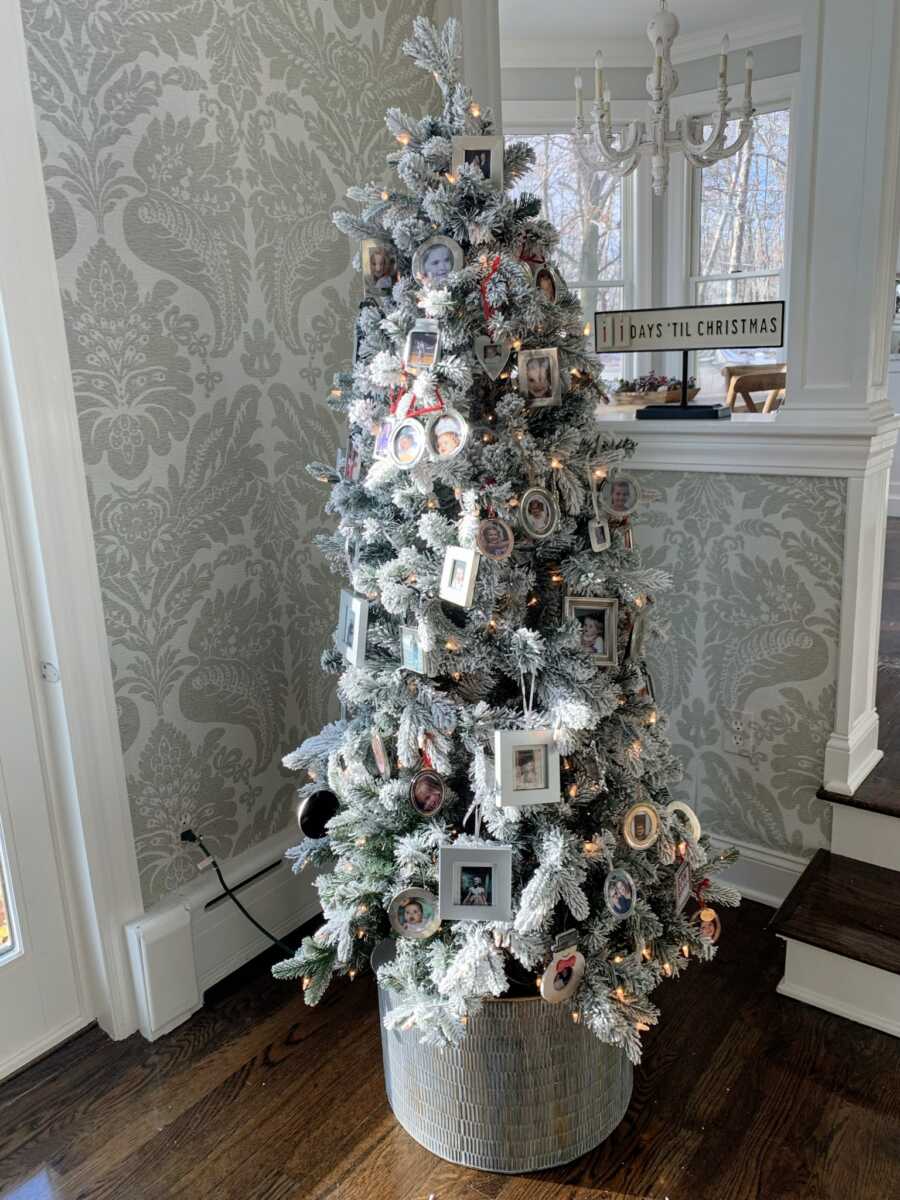 Tall green and white Christmas Tree decorated with family portraits and warm lights