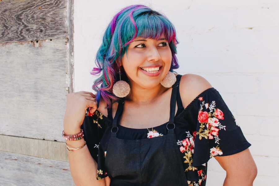 woman with blue hair smiling while looking to the side