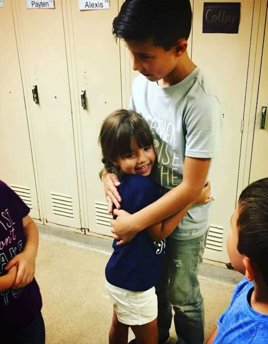 siblings hugging in the hallway
