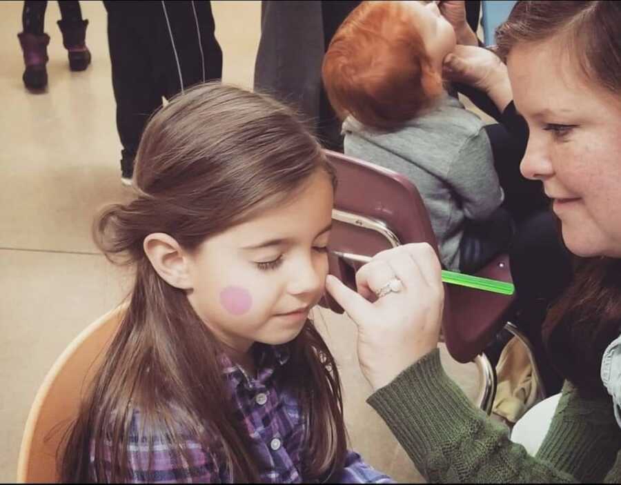 teacher painting young girl's face