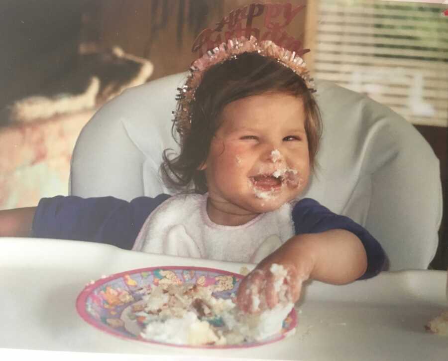 little girl in high chair with cake on her face