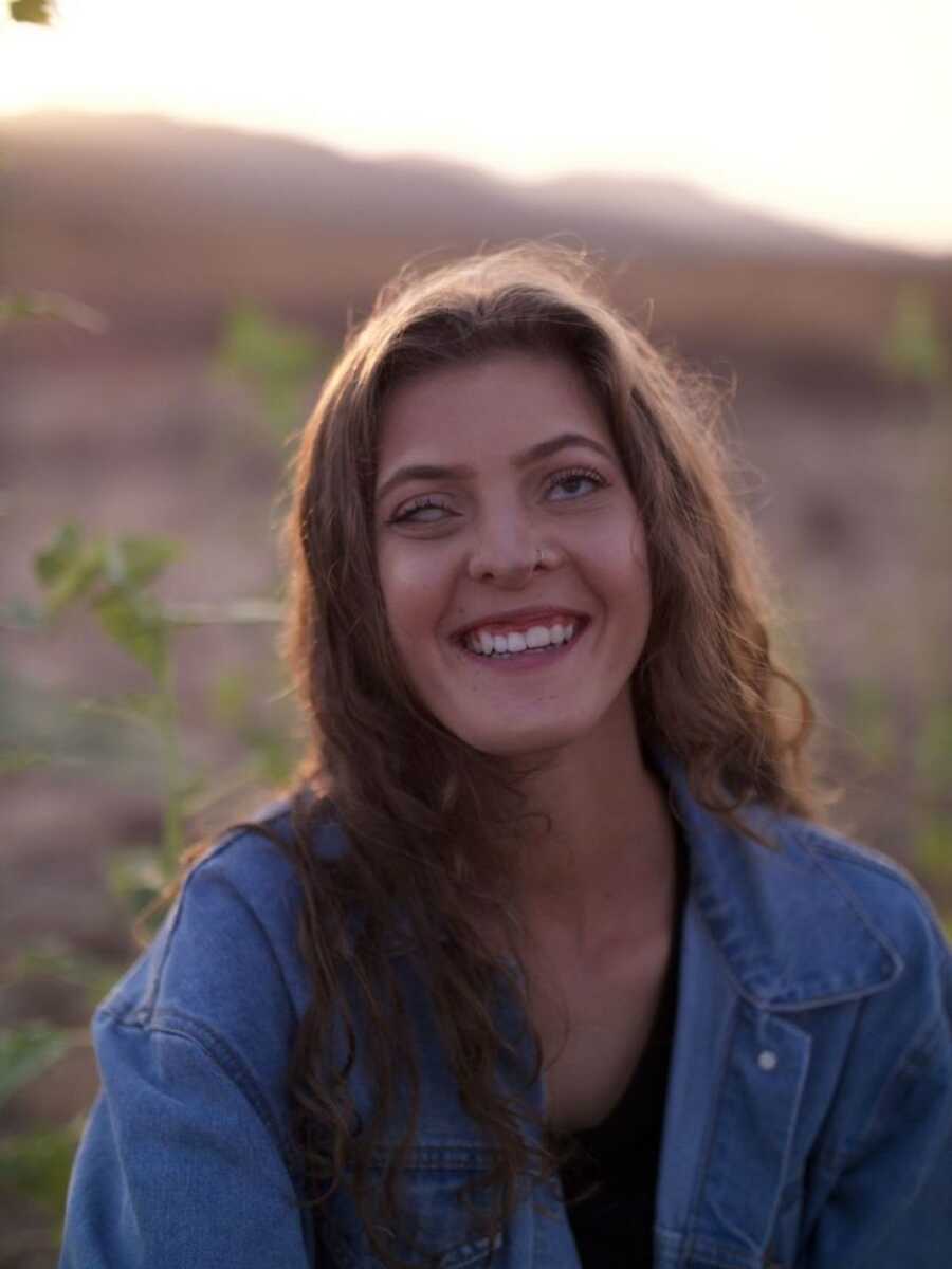 woman with rare genetic disorder sitting in a field smiling