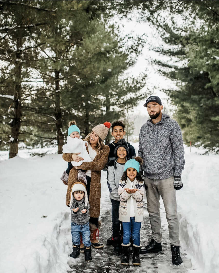 mother of five and second husband pose for winter family portrait with 5 children outdoors in the snow 