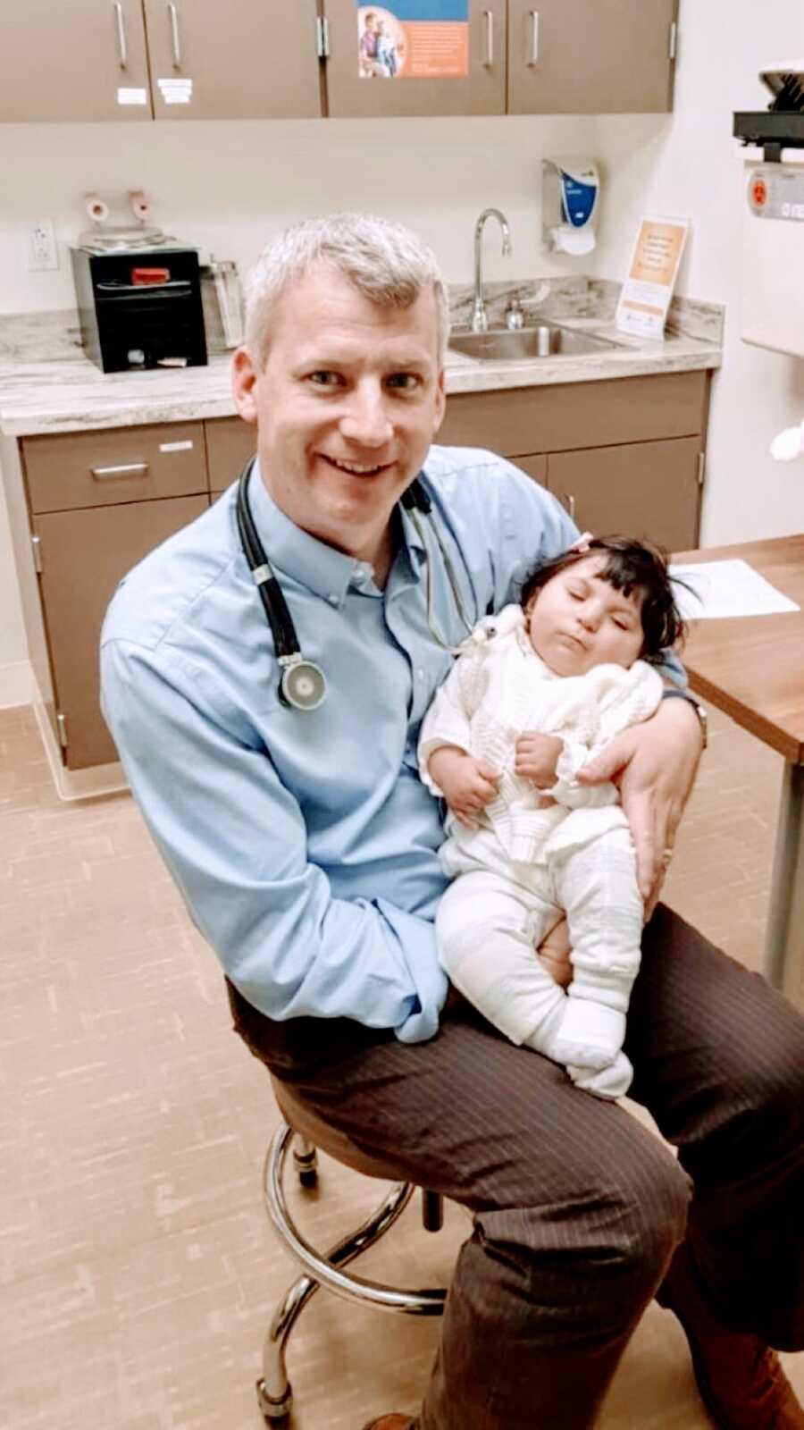 Doctor holds the baby girl he saved through rare in womb surgery