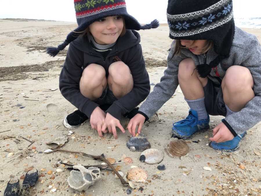 两个男孩在海滩上捡贝壳