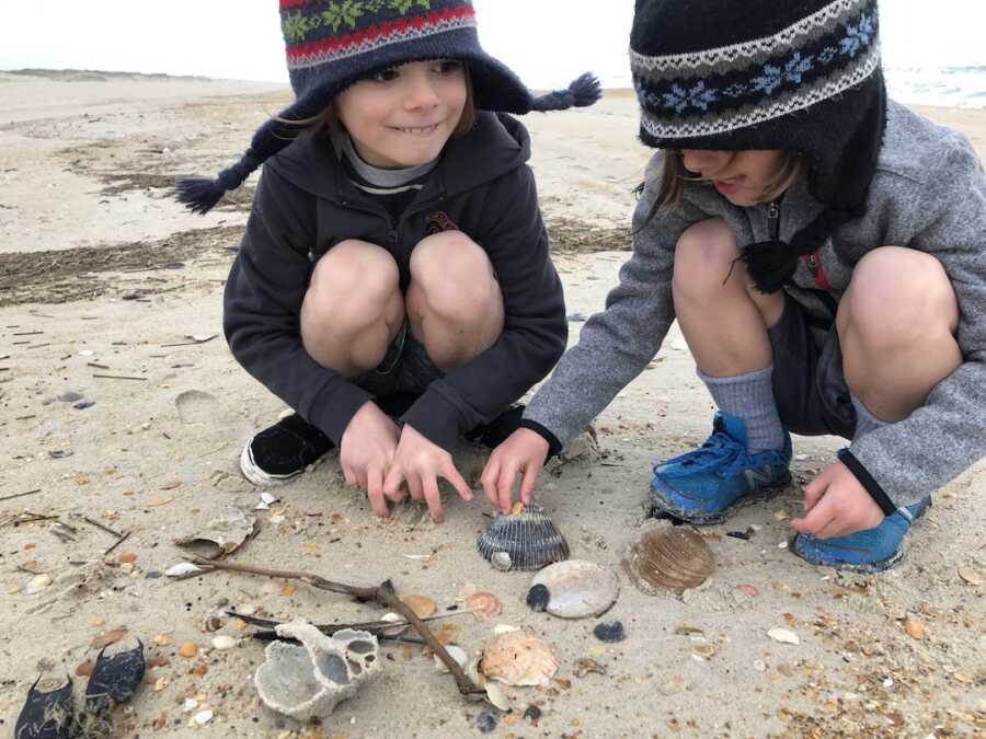 two boys collecting seashells at the beach