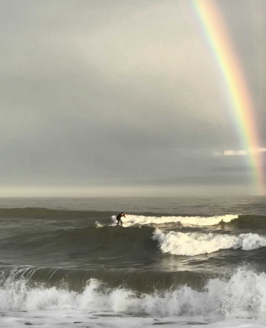 男人在彩虹的背景下冲浪