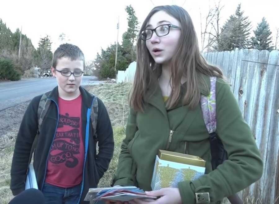 teen girl with her little brother receiving the gift cards 