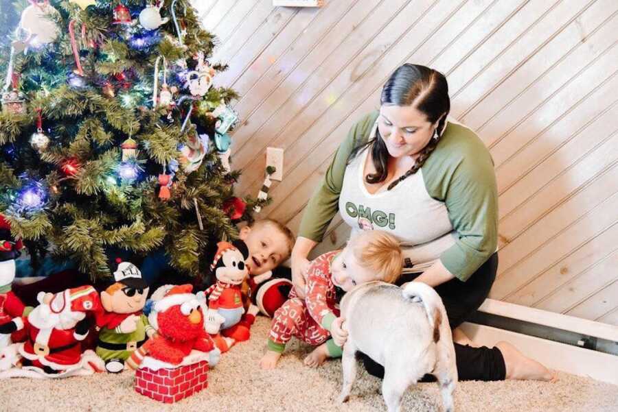 mom sitting by the Christmas tree with her two kids and dog