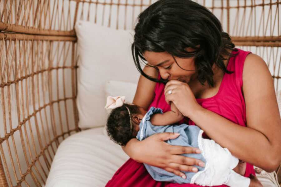 mom holding her child close and giving her a kiss on the hand