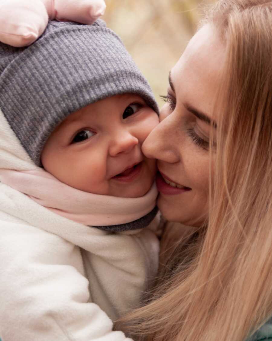 baby smiling and being held by mom closely