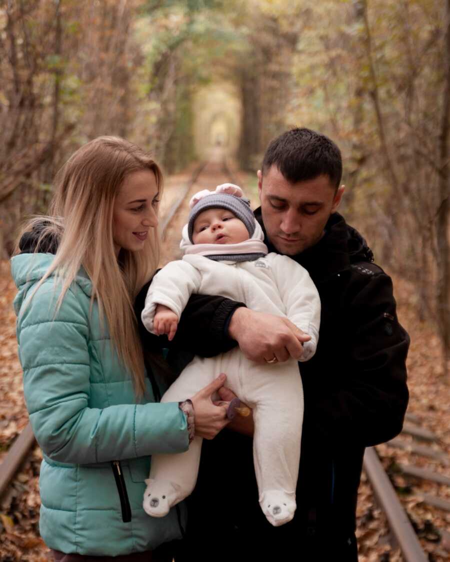 mom and dad posing with their baby daughter