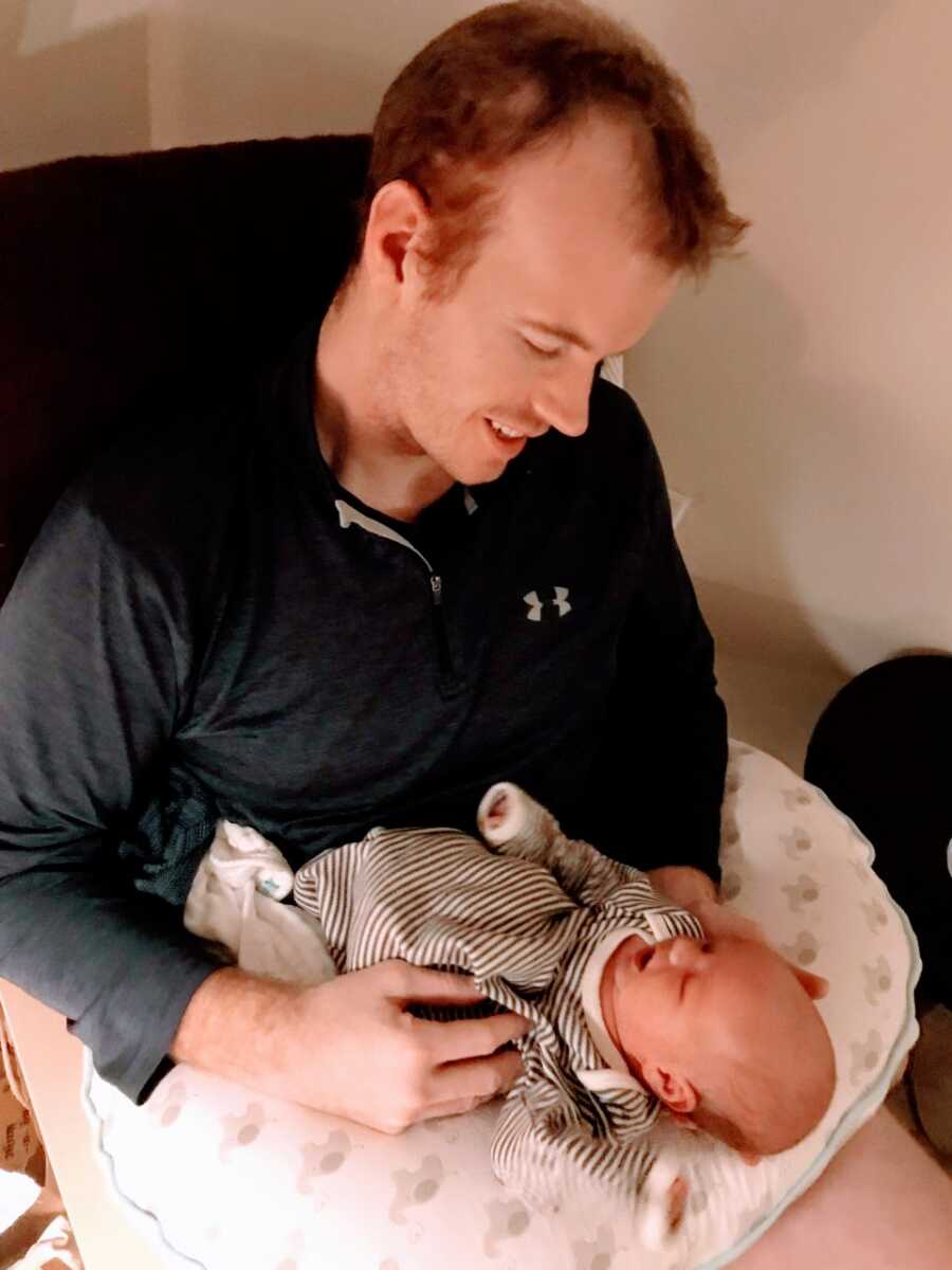Man stares down in awe at his newborn child