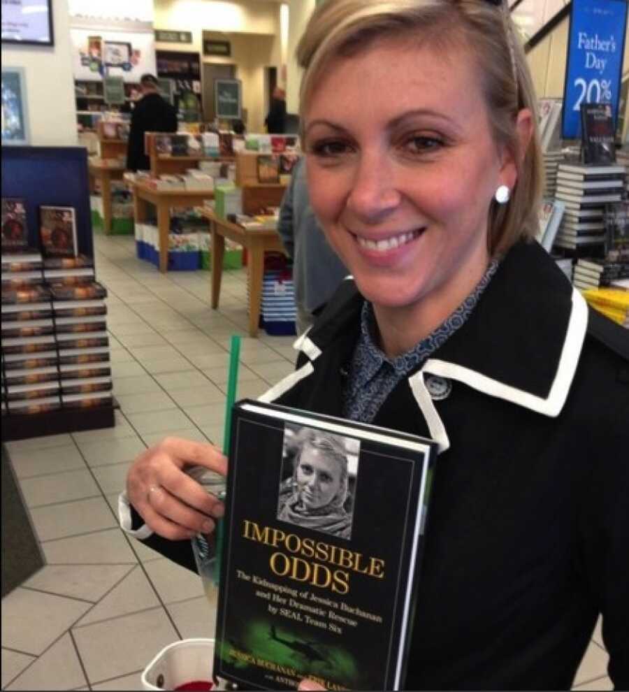 Jessica holds her published book, 'Impossible Odds,' about her survival.