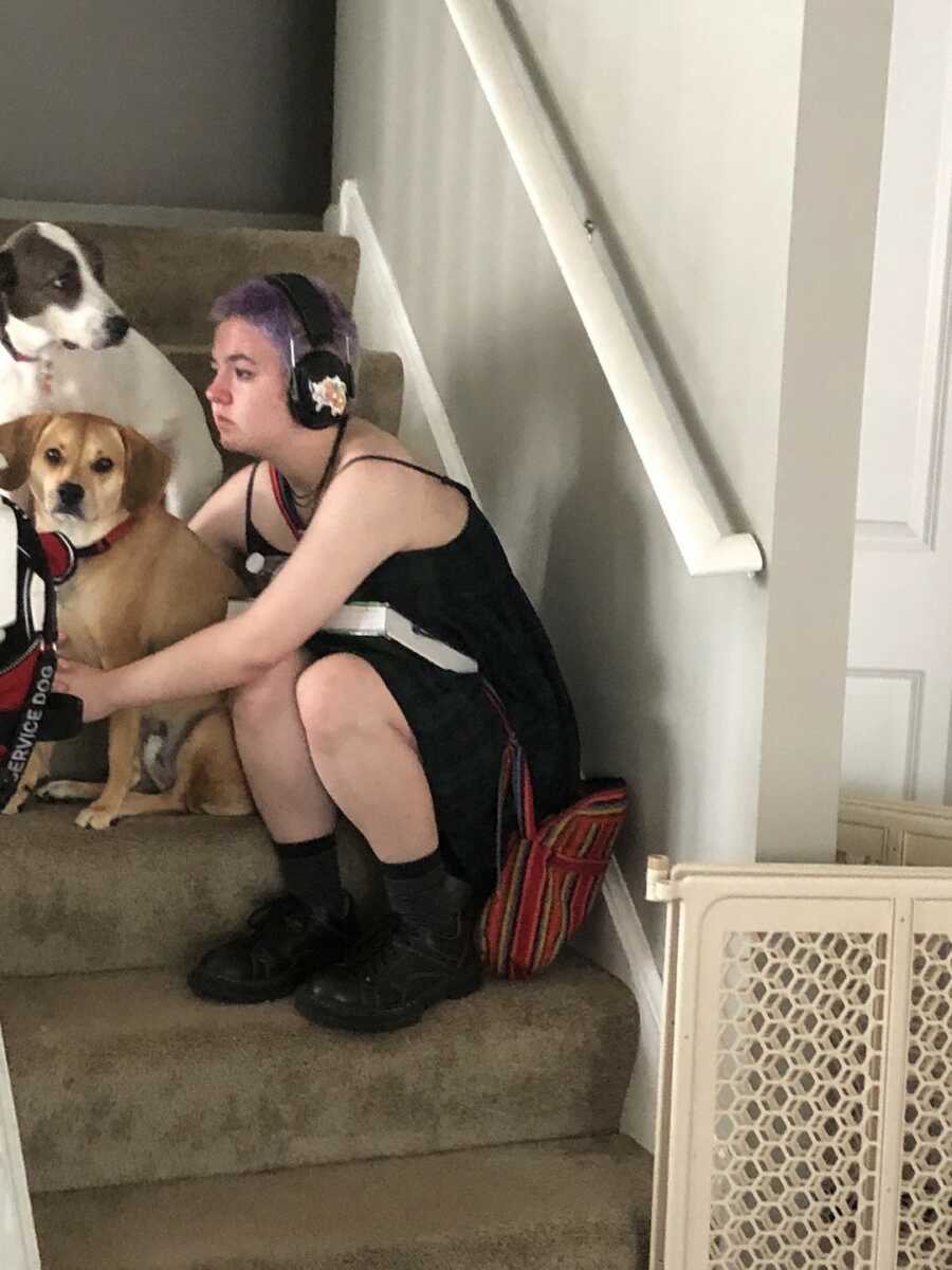 young teen sitting on the stairs with headphones and dogs