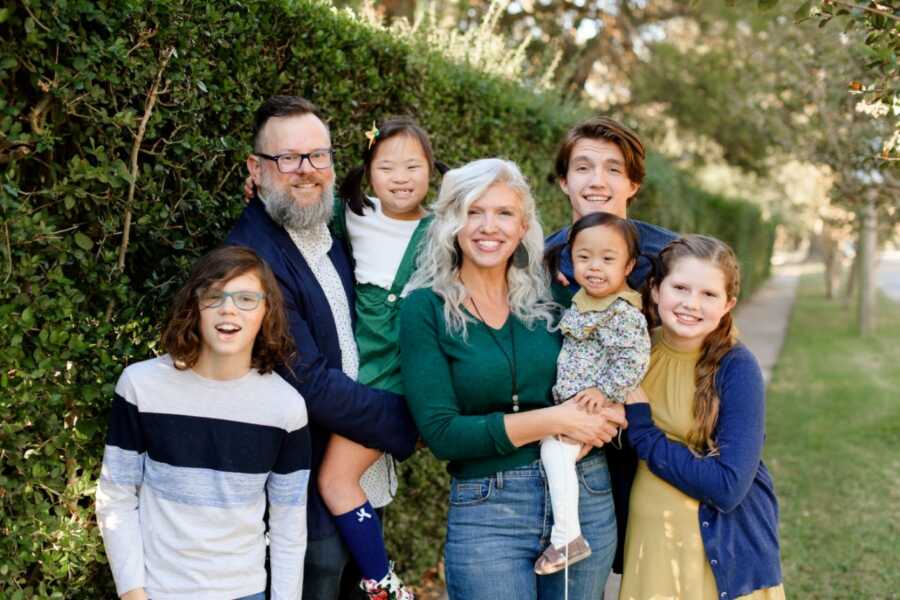 family photo in front of a green shrub