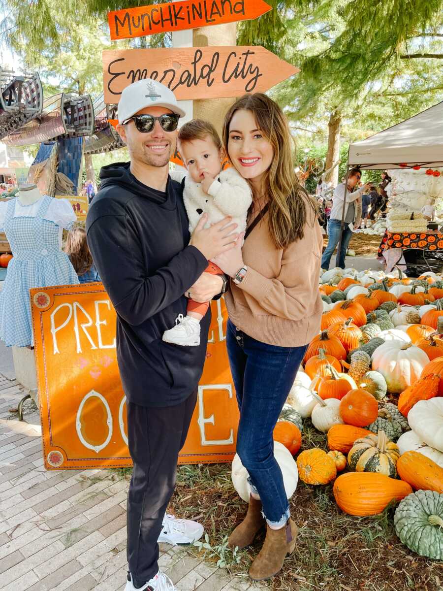 parents with their adopted kid in the pumpkin patch